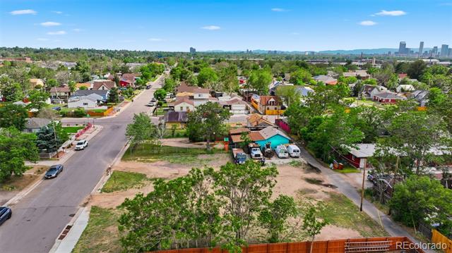 Aerial view of a vacant lot among homes, with the Denver skyline in the distance.