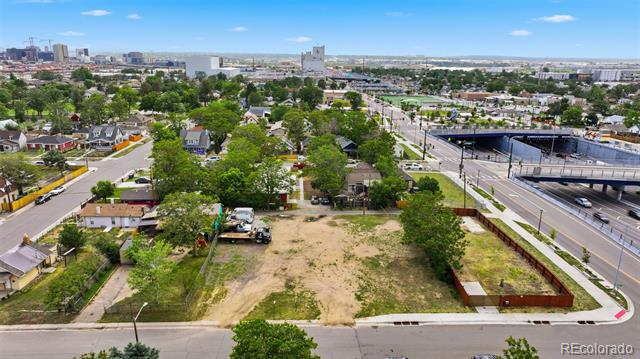 Aerial view of a vacant lot beside a highway, with a city skyline in the distance.