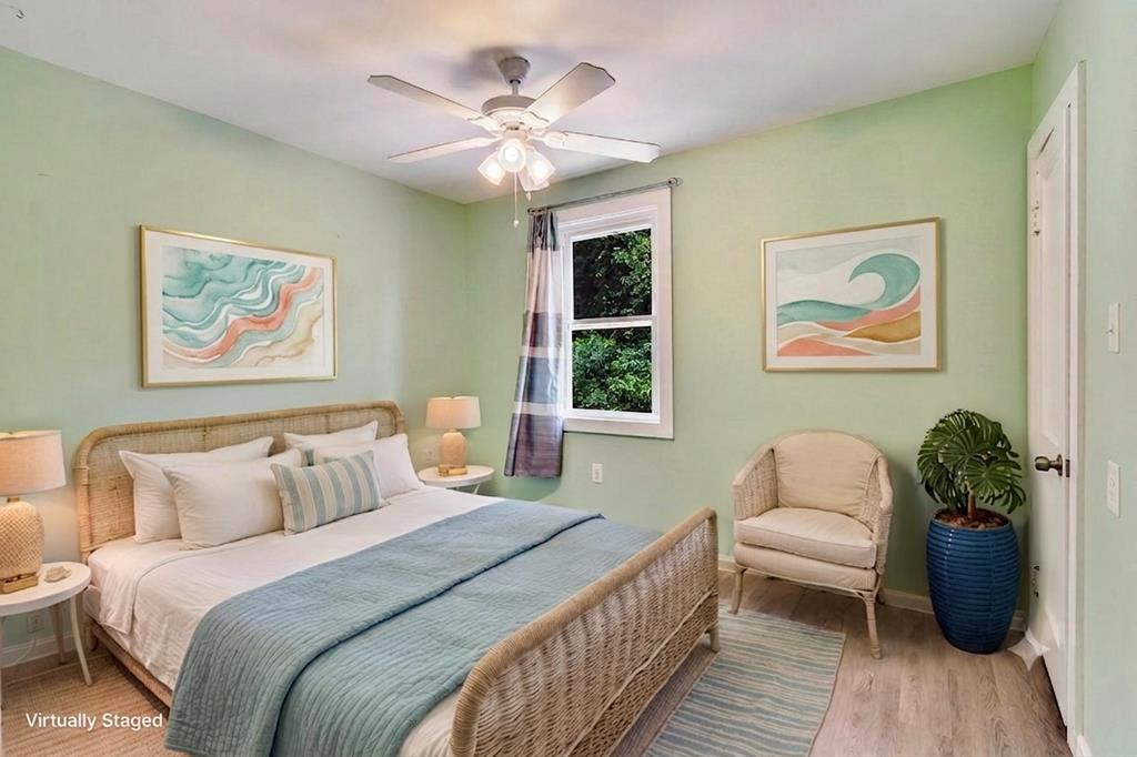 Bedroom with a wicker bed, blue bedding, pale green walls, and abstract artwork.