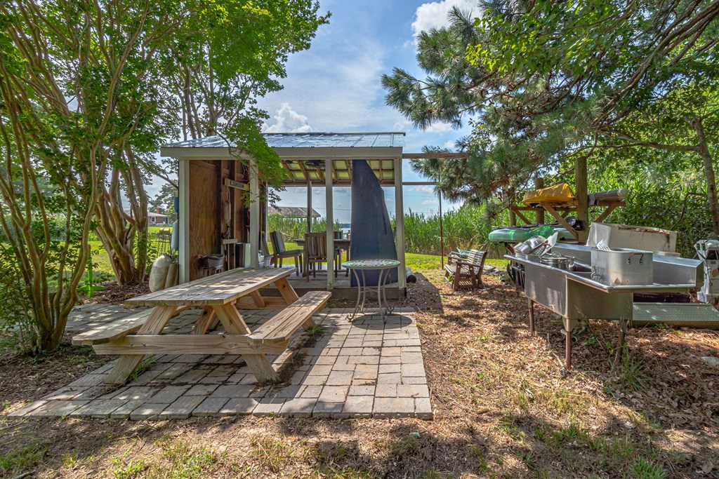 Outdoor patio with a covered pergola, picnic table, and stainless-steel cooking station.