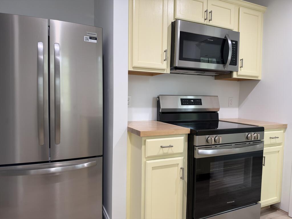 Kitchen with cream cabinets, wood countertops, and stainless steel appliances.