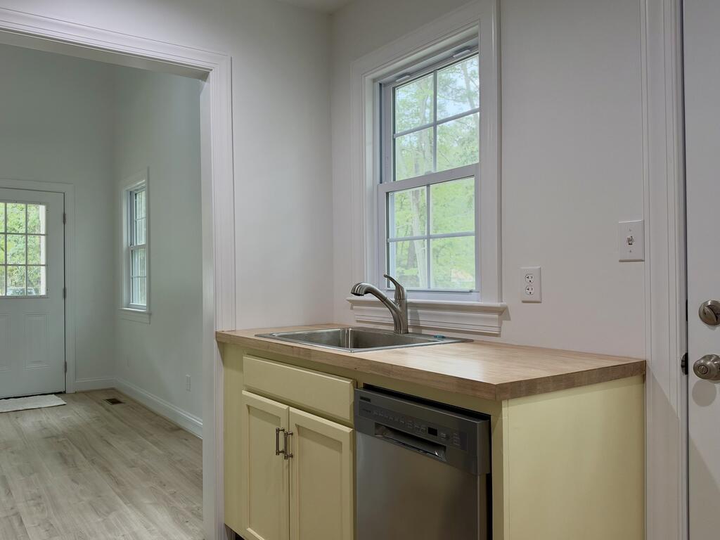 Kitchen sink and dishwasher beneath a window, with an entry door nearby.
