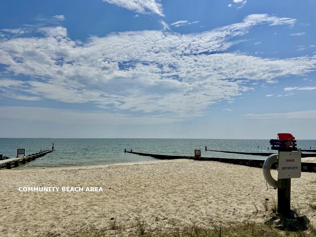 Community beach with sandy shore, wooden piers, and a lifebuoy beside the water.