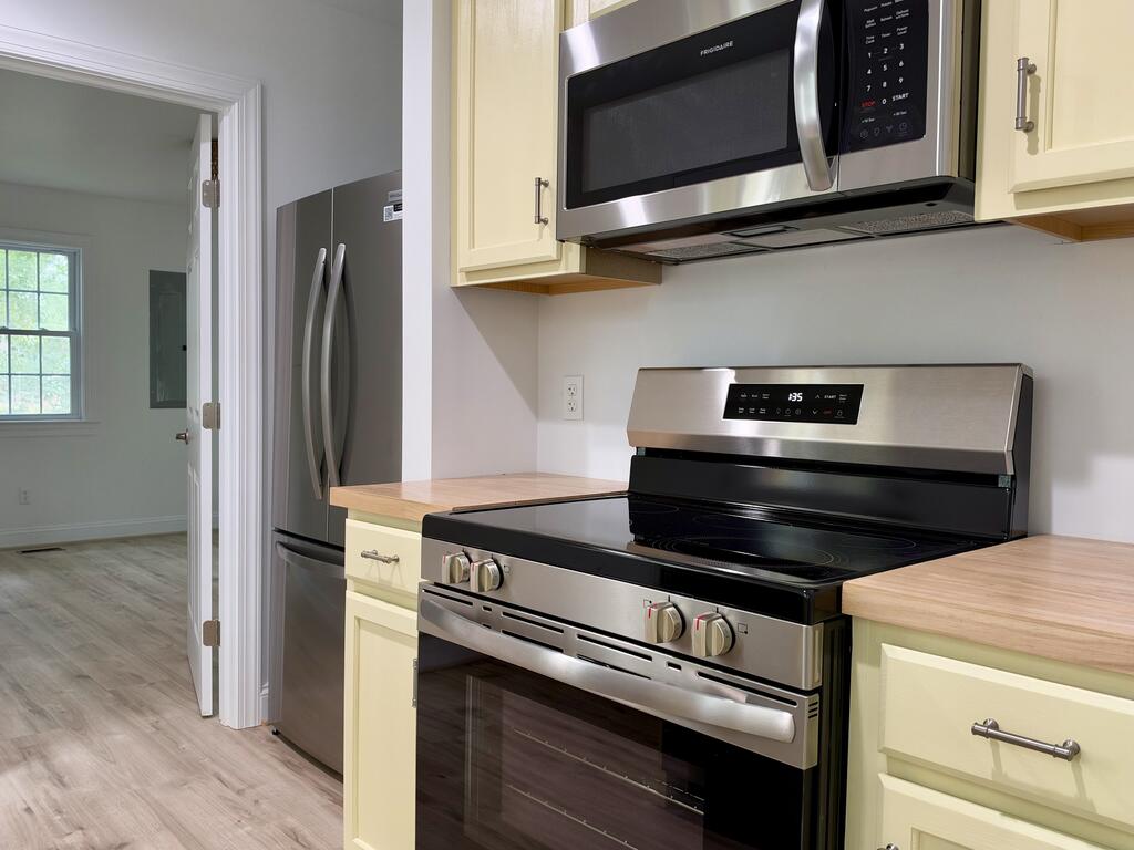 Kitchen with pale cabinets, wood countertops, and stainless steel appliances.