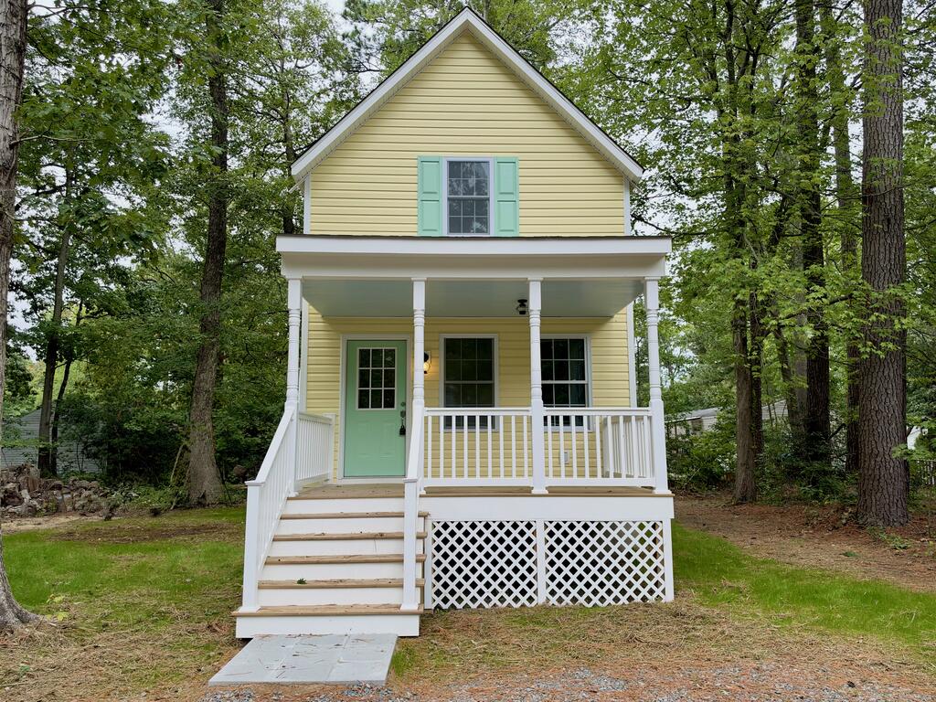 Yellow two-story home with a covered front porch, white railings, and mint-green door.