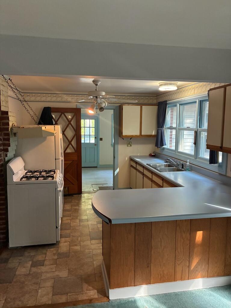 Kitchen with a large peninsula, gas range, and sink beneath windows.