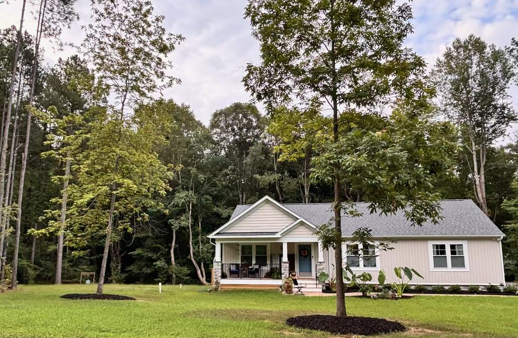 Single-story home with a covered porch and blue front door, surrounded by mature trees.