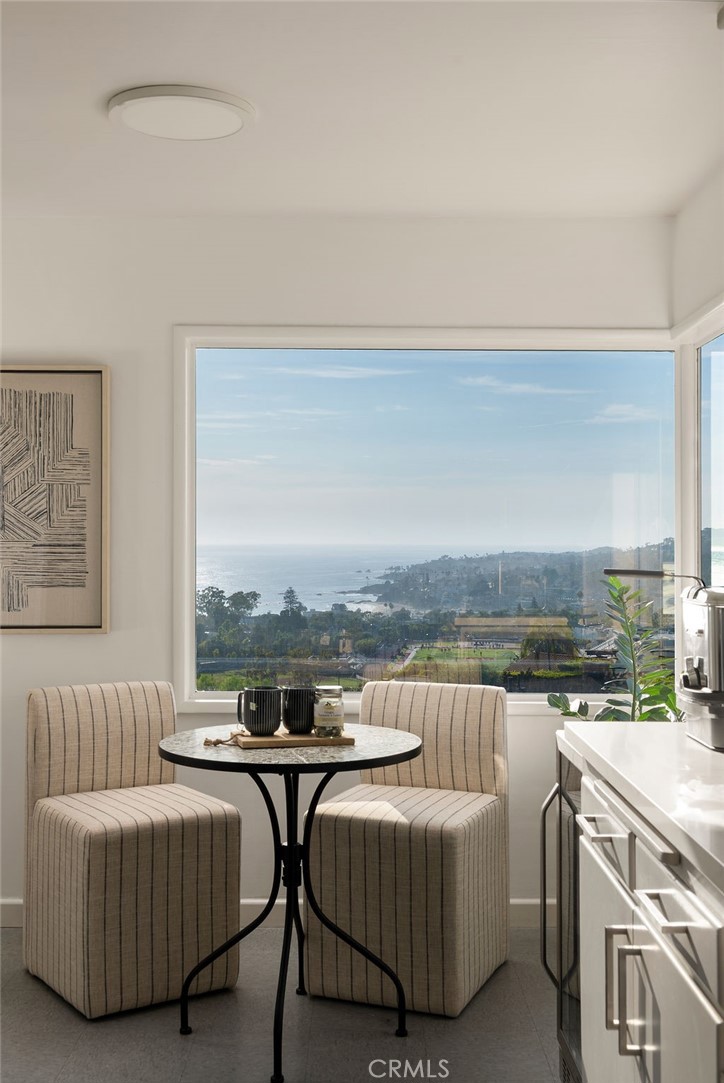 Kitchen dining nook with striped chairs and a large window overlooking the ocean and Laguna Beach coastline.