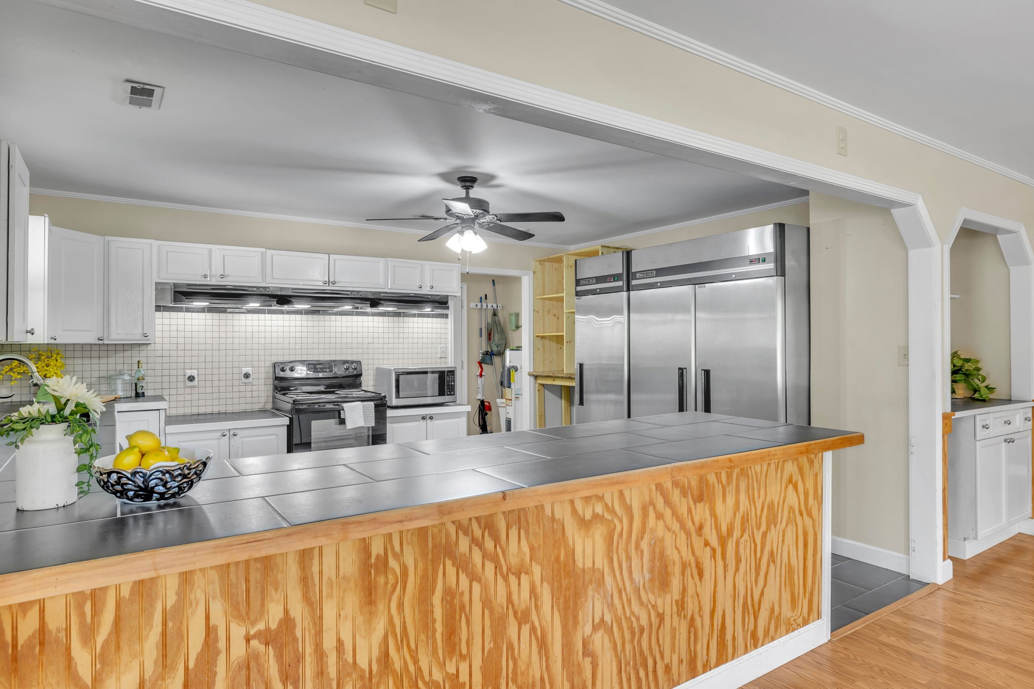 Kitchen with large stainless steel refrigerators and a wide wood-front island with a tiled countertop.