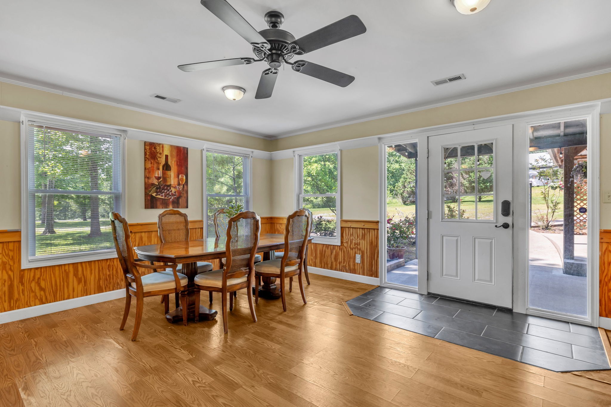Dining room with a wooden table and chairs beside windows and a glass-paneled exterior door.