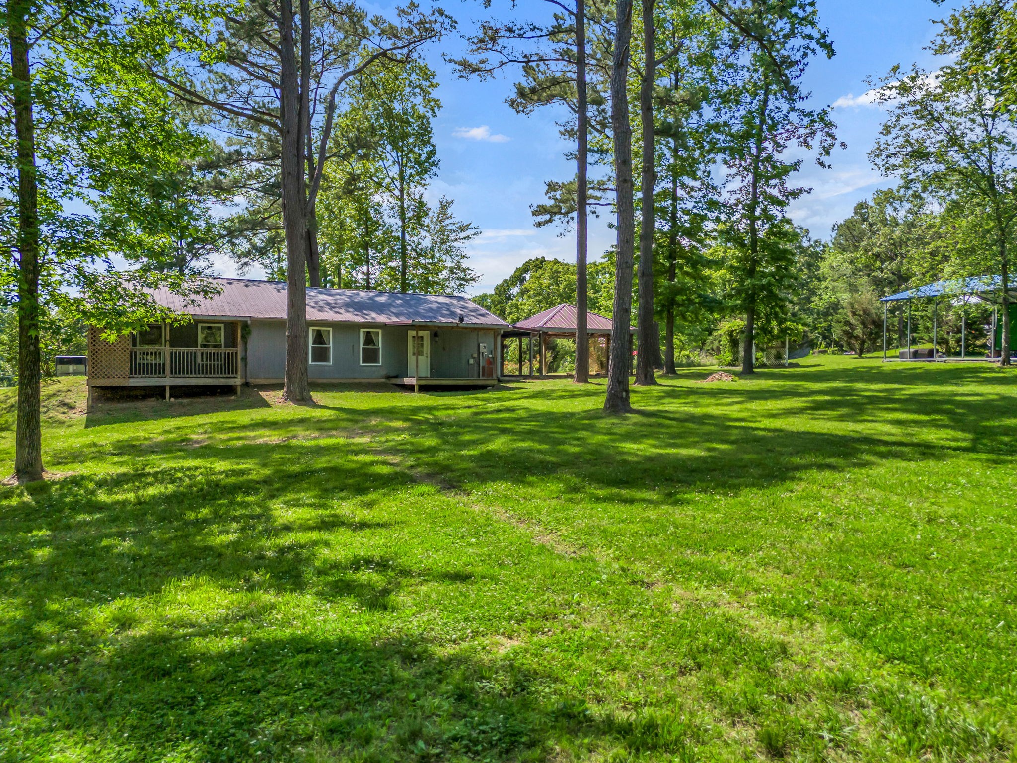 Single-story gray house with a covered porch on a broad, tree-shaded lawn.