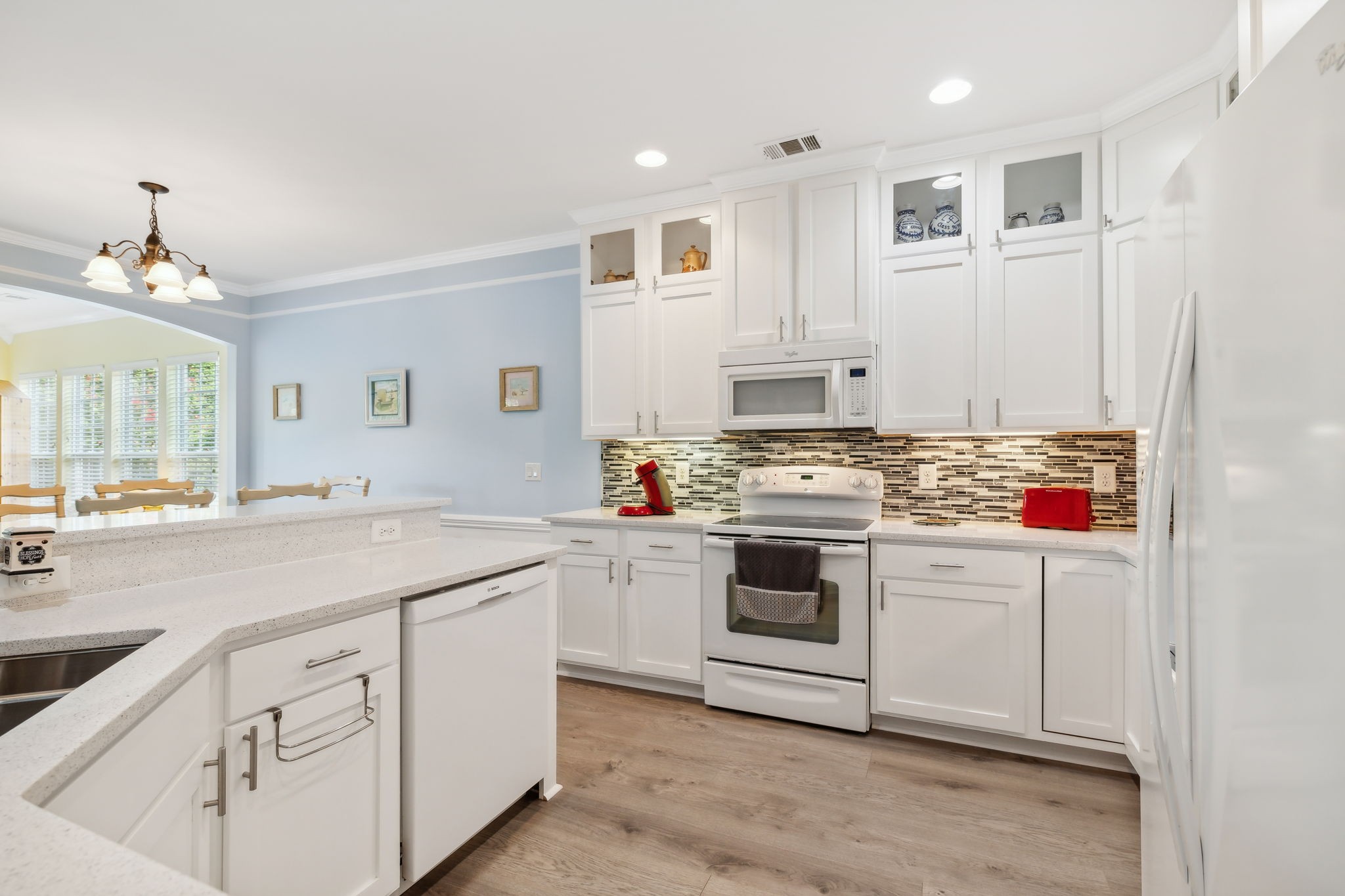 Kitchen with white cabinets and appliances, a mosaic tile backsplash, and a large peninsula.