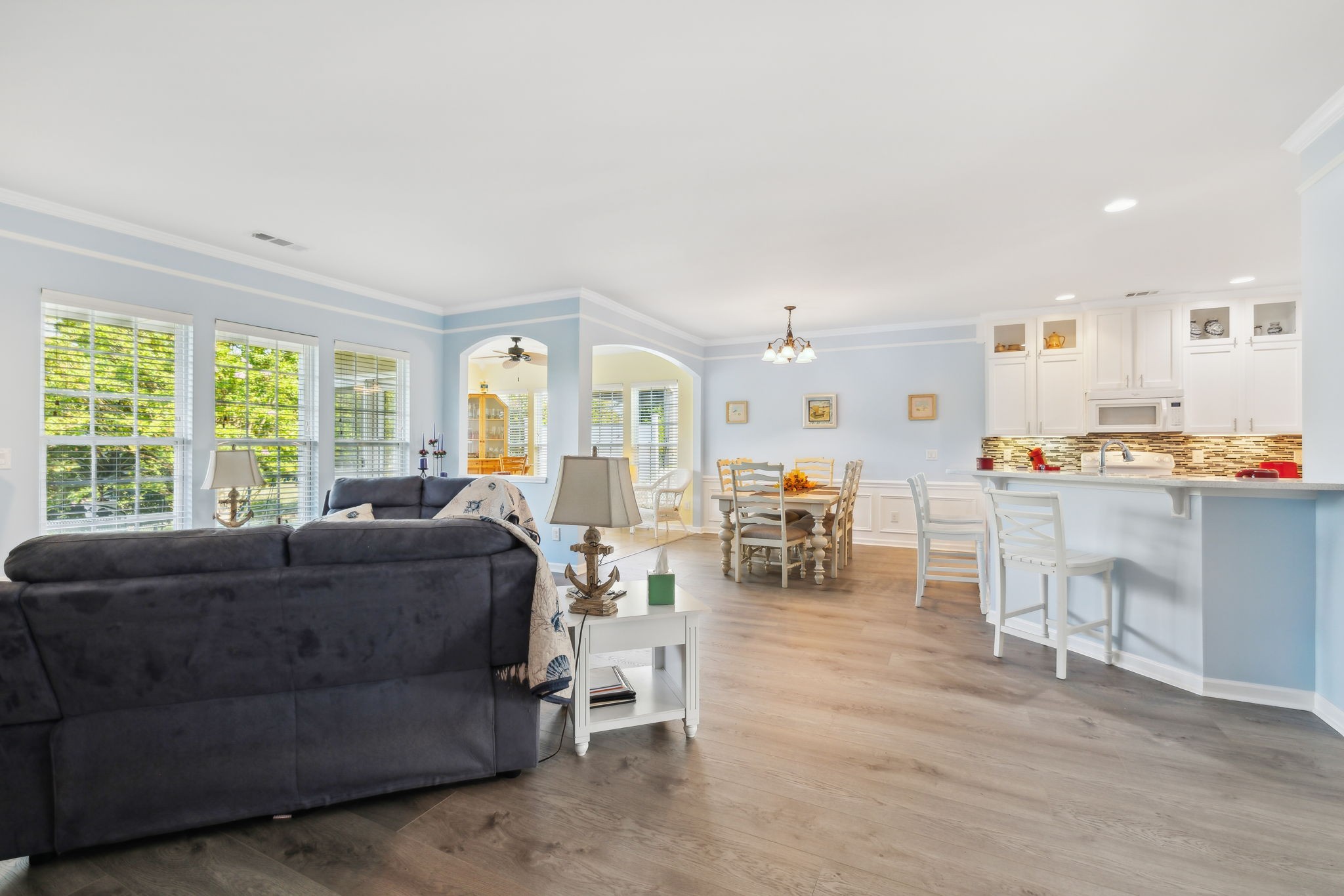 Open-plan living and dining area beside a kitchen with white cabinetry and a breakfast bar.