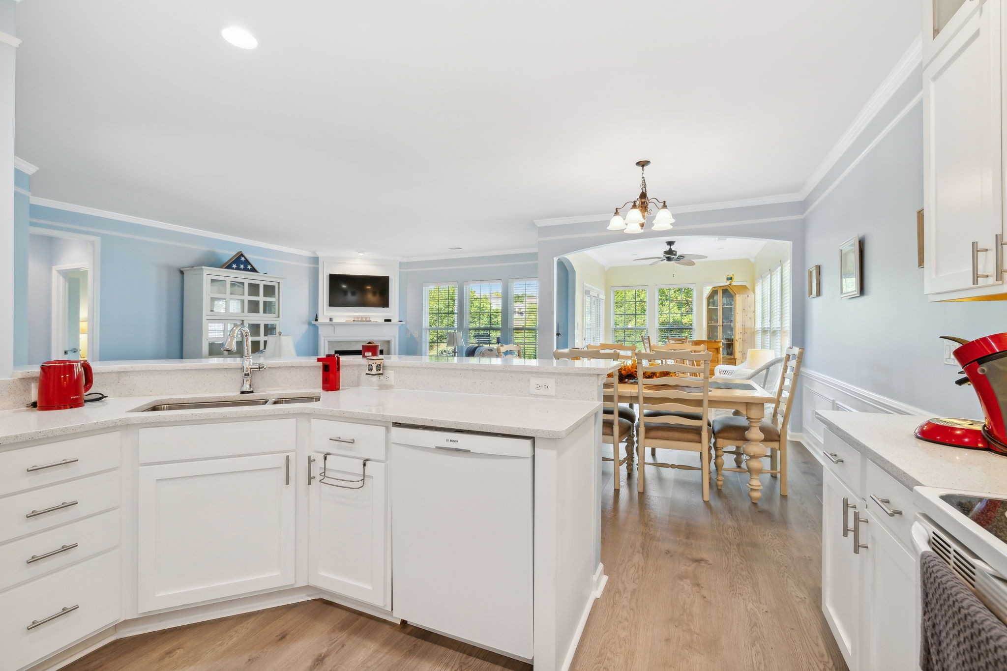 Kitchen with white cabinets and a large peninsula opens to a dining area and living room.
