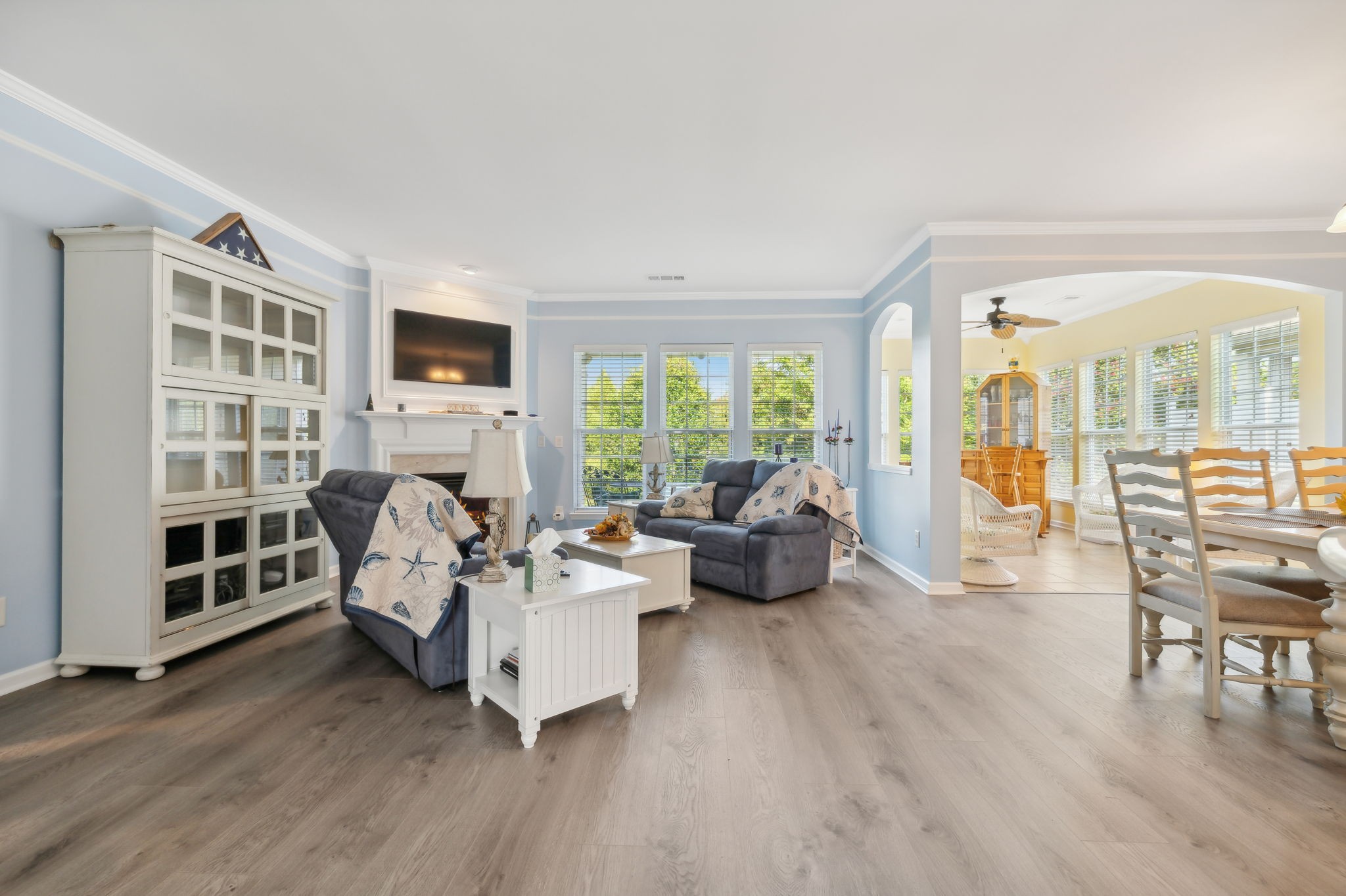 Living room with gray sofas, a fireplace, and an open connection to a bright dining area.