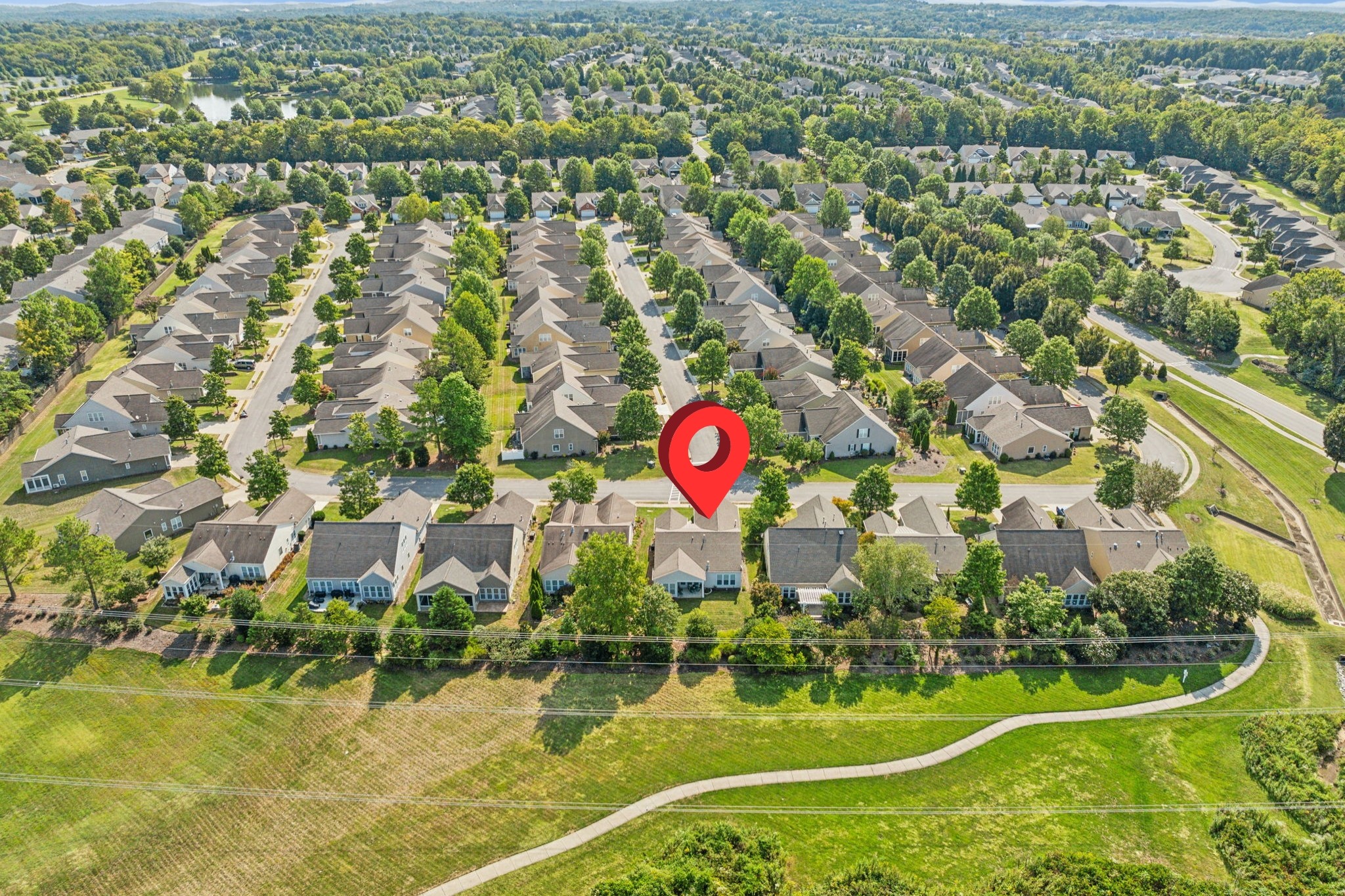 Aerial neighborhood view with a red map pin marking a home among rows of houses.