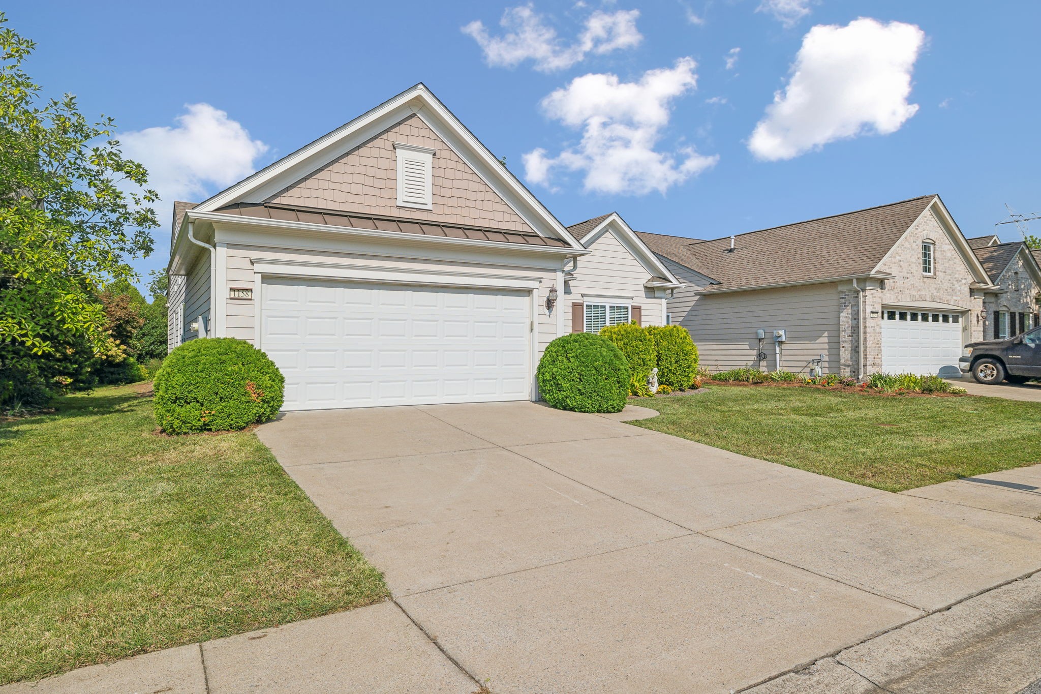 House exterior with a two-car garage, broad driveway, trimmed shrubs, and visible number 1158.