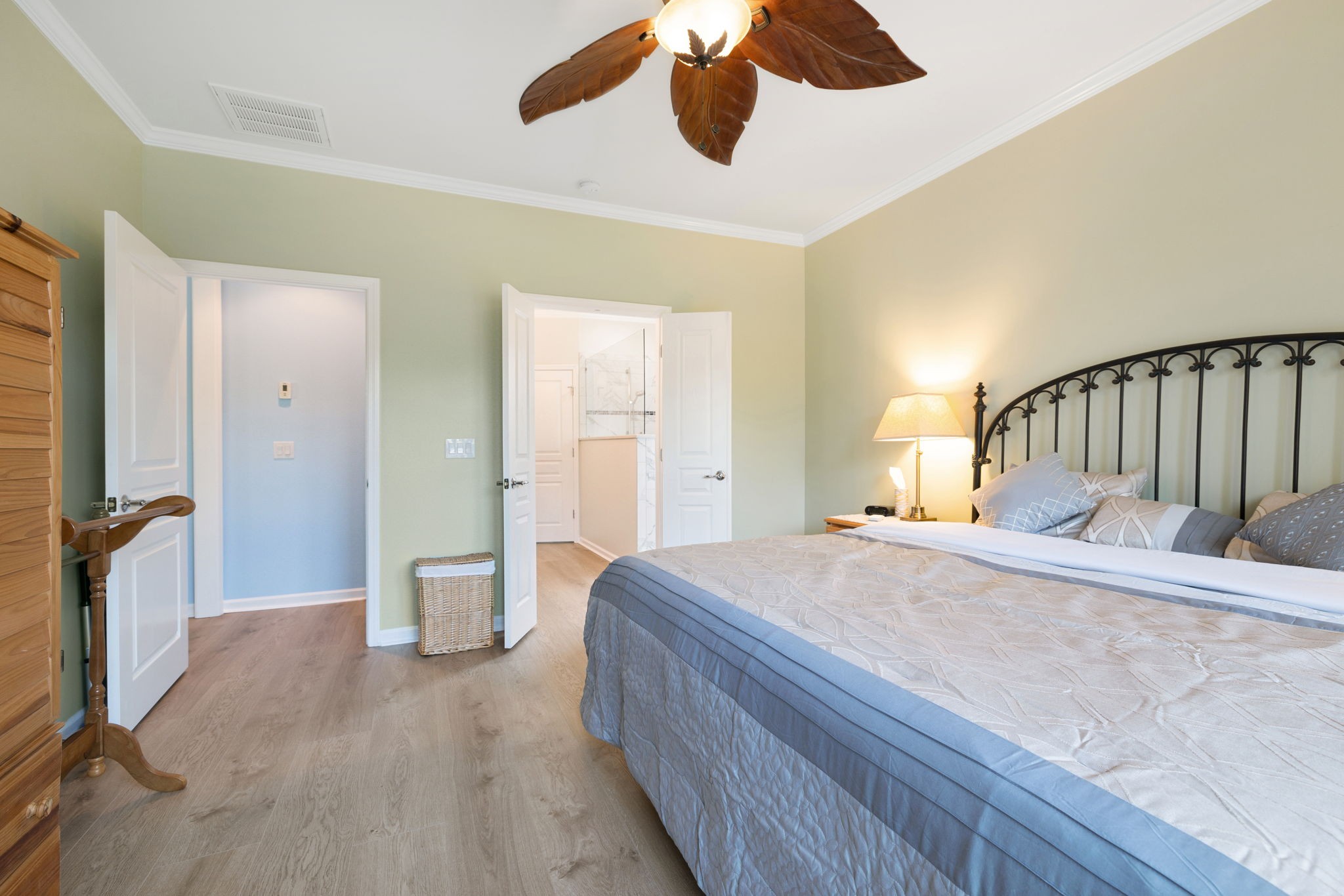 Bedroom with a large bed, black metal headboard, and open doorway to the en-suite bathroom.