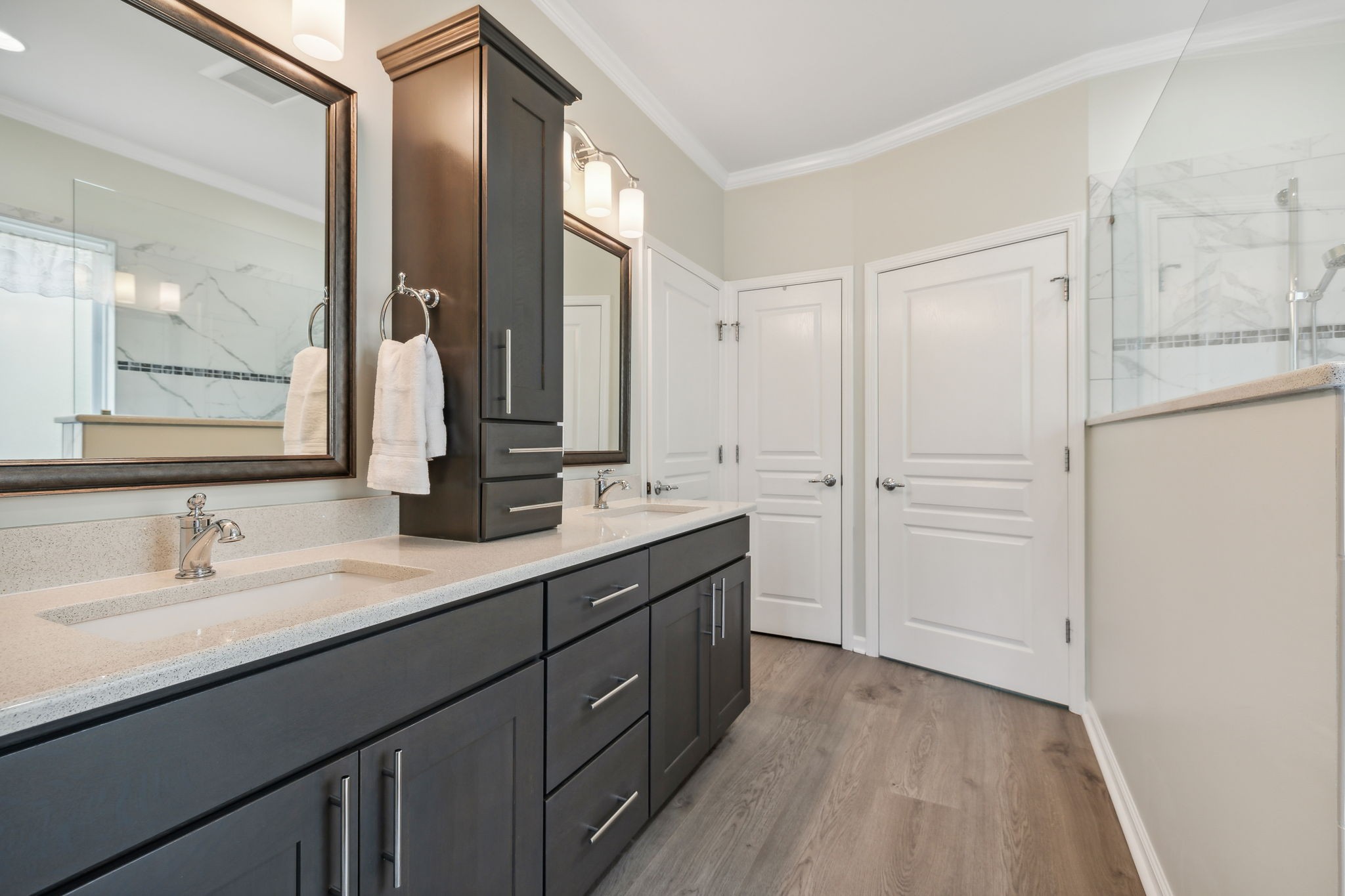 Bathroom with a long dark vanity, framed mirrors, and a glass shower.