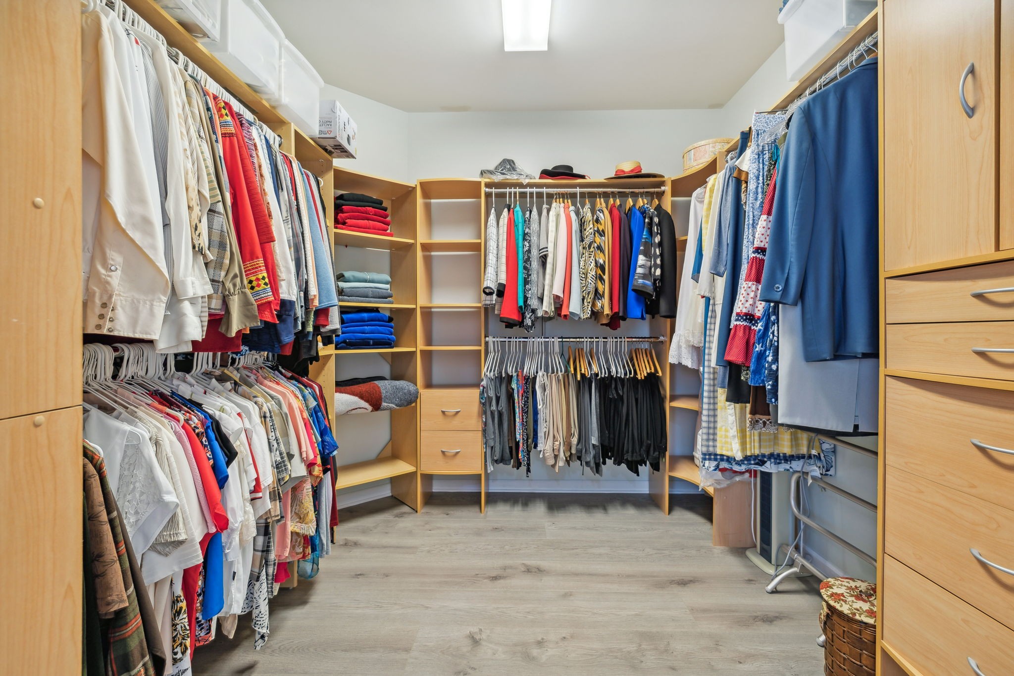 Walk-in closet with extensive wood shelving and clothing on multiple hanging rails.