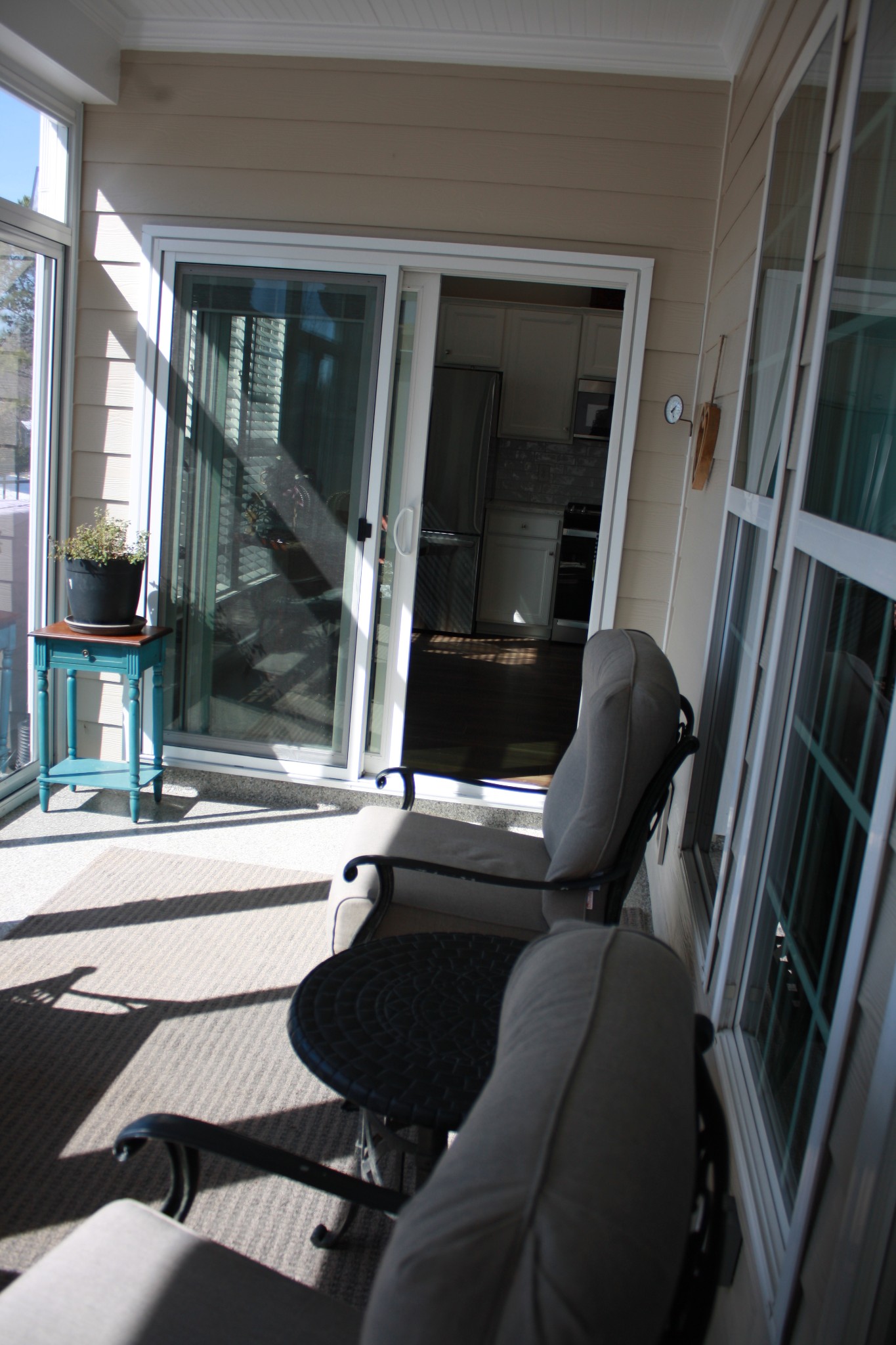 Sunroom with cushioned chairs, a round table, and a sliding glass door to the kitchen.
