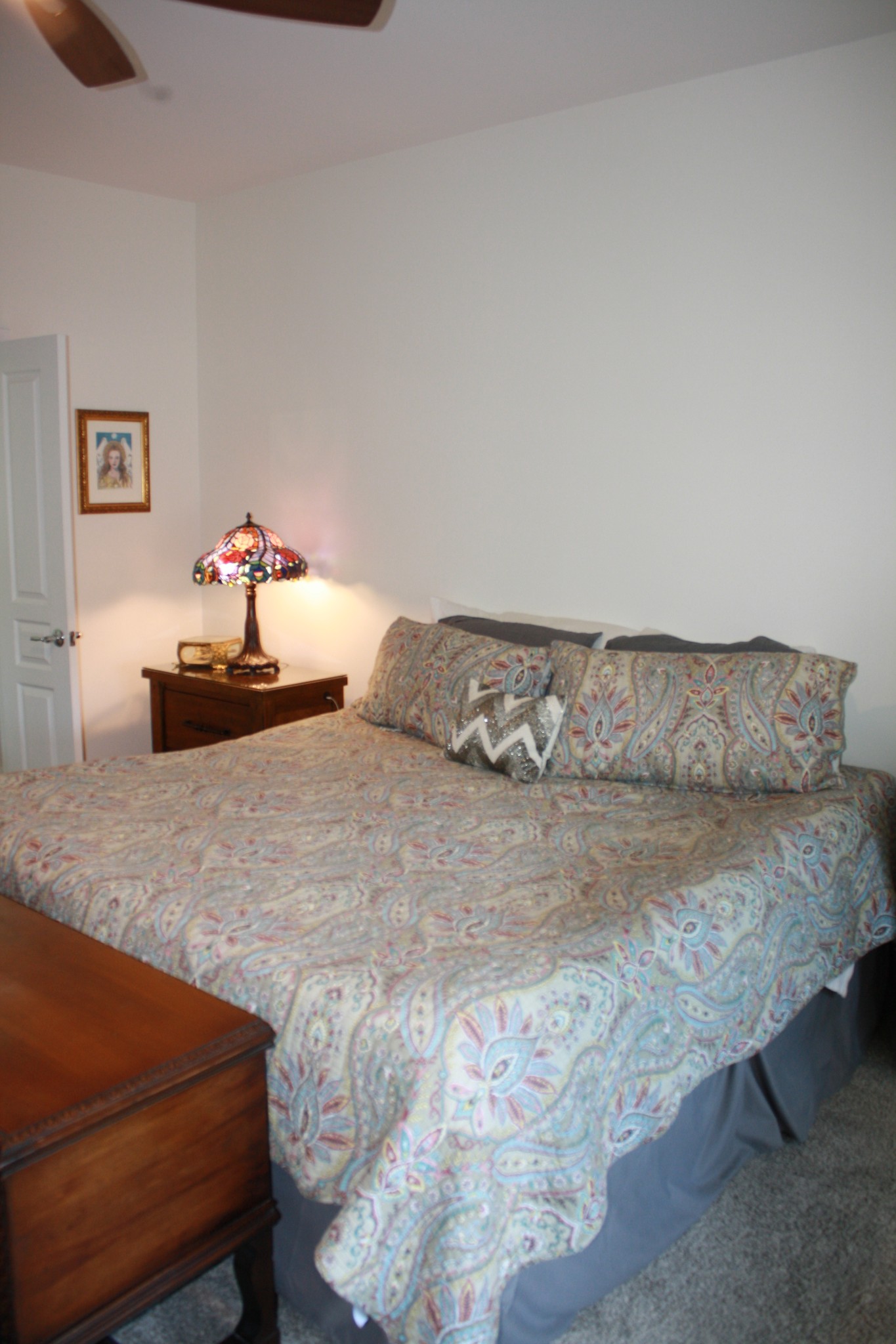 Bedroom with a large paisley-covered bed and a stained-glass lamp on the nightstand.