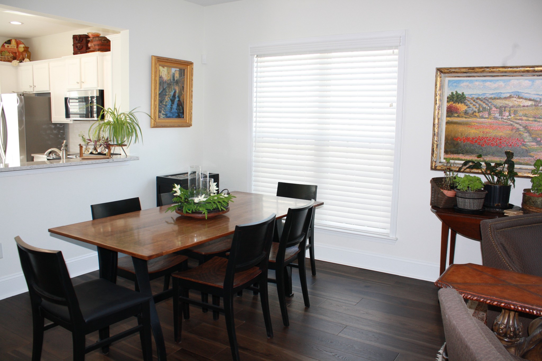 Dining room with a dark wood table, black chairs, and large window with white blinds.