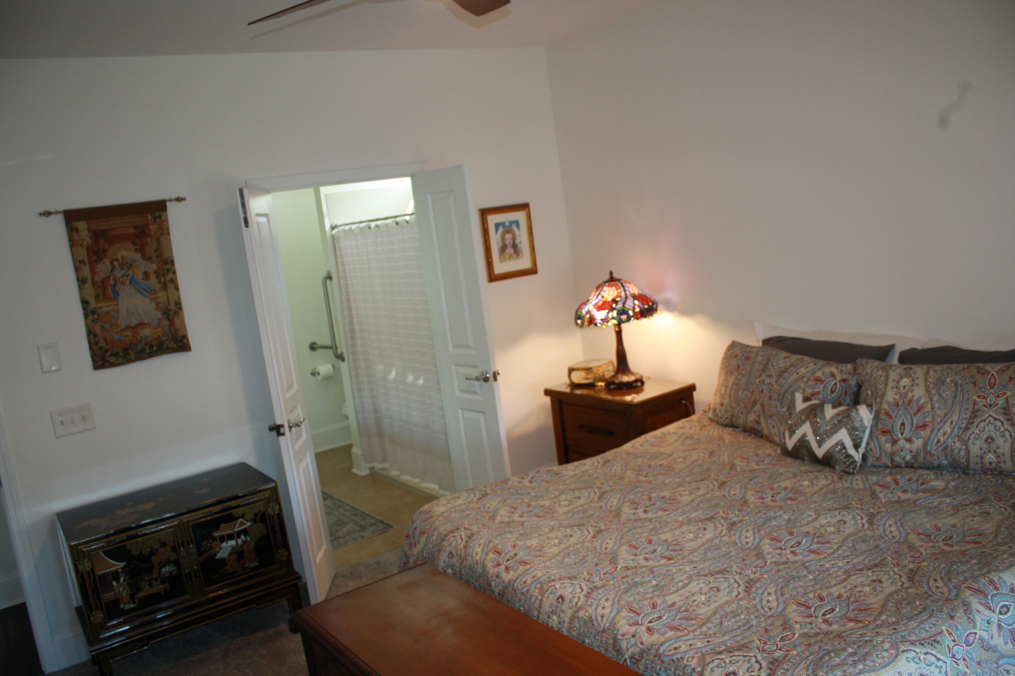 Bedroom with a paisley-covered bed beside an open doorway to a bathroom.