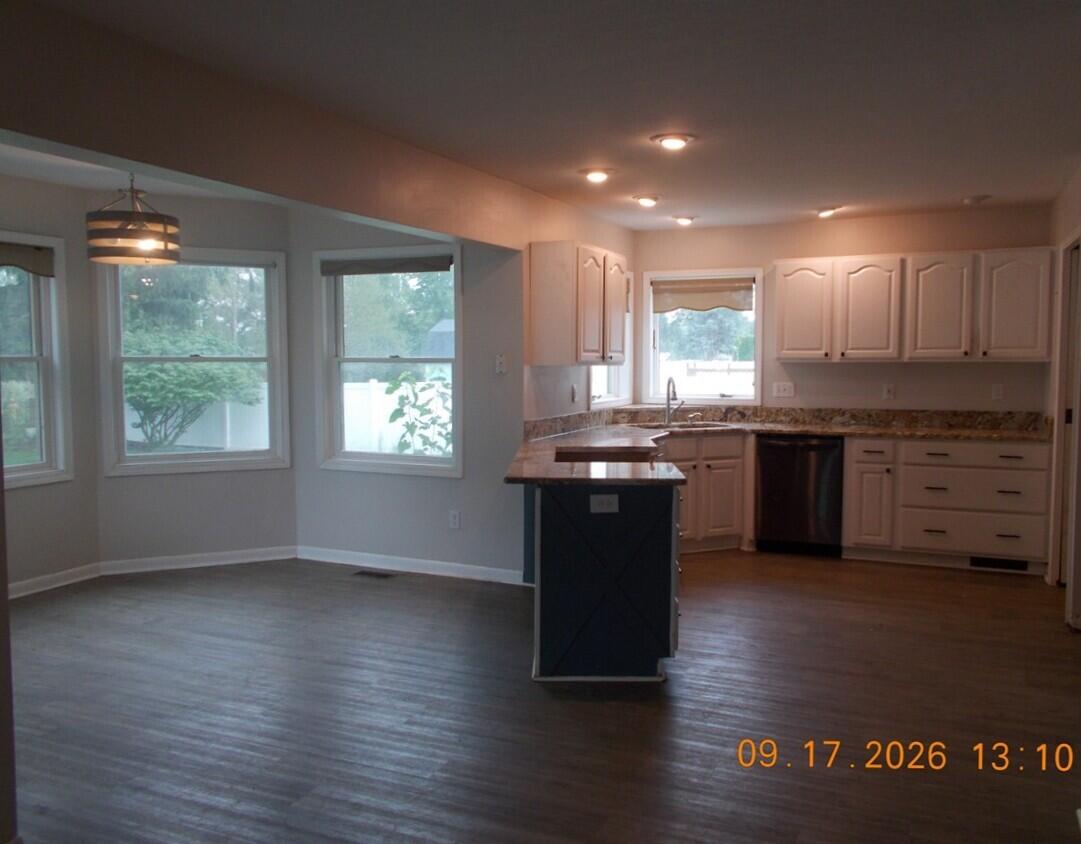 Kitchen and dining area with a central island, white cabinets, and large windows.