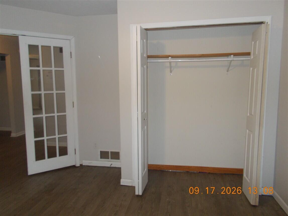 Vacant room with an open closet, French doors, and wood-look flooring.