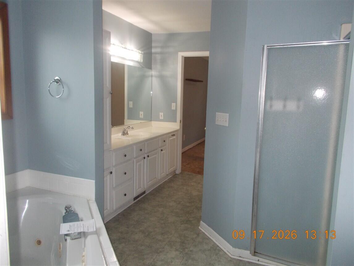Bathroom with a long white vanity, built-in bathtub, and frosted-glass shower enclosure.