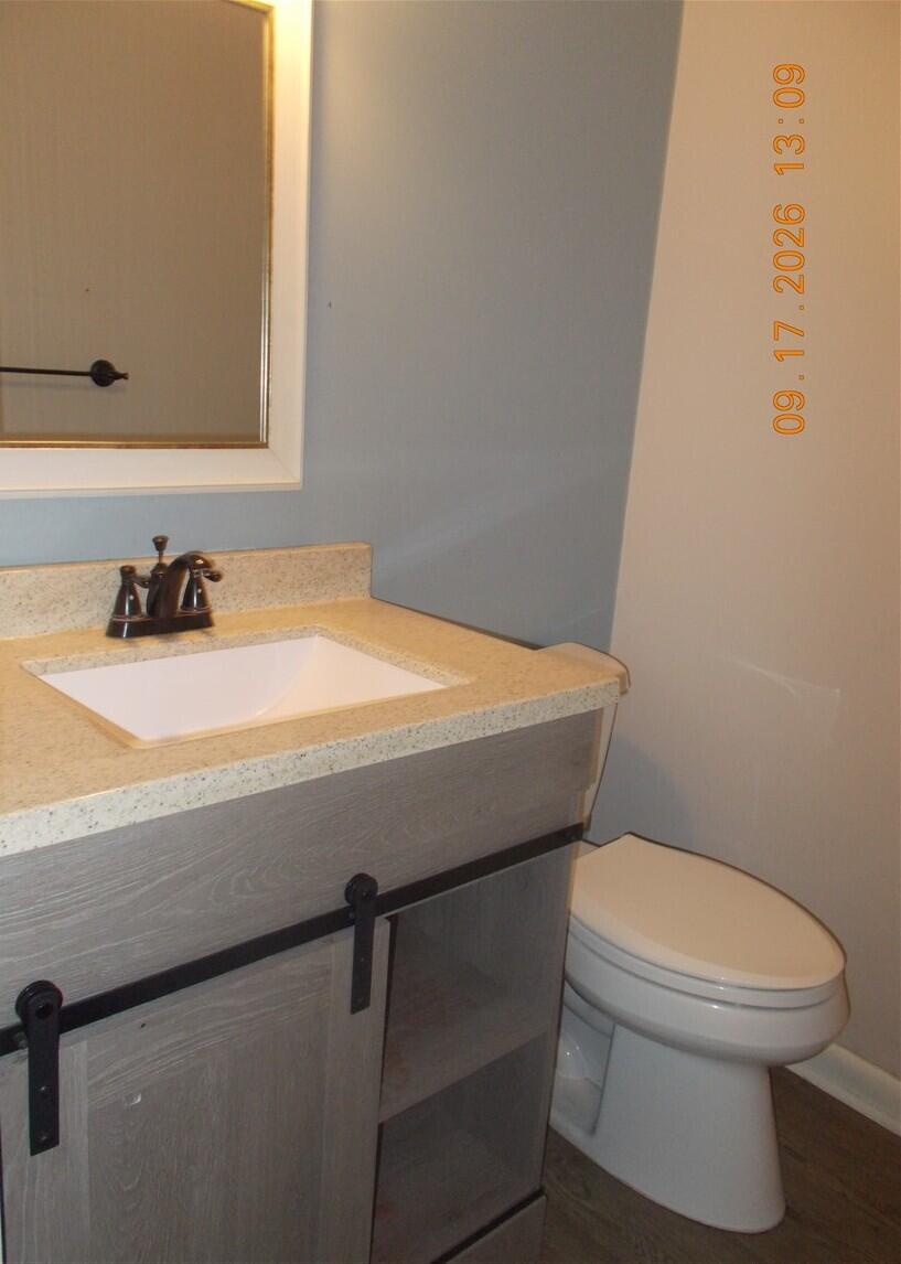 Bathroom vanity with beige countertop and white sink beside a toilet.