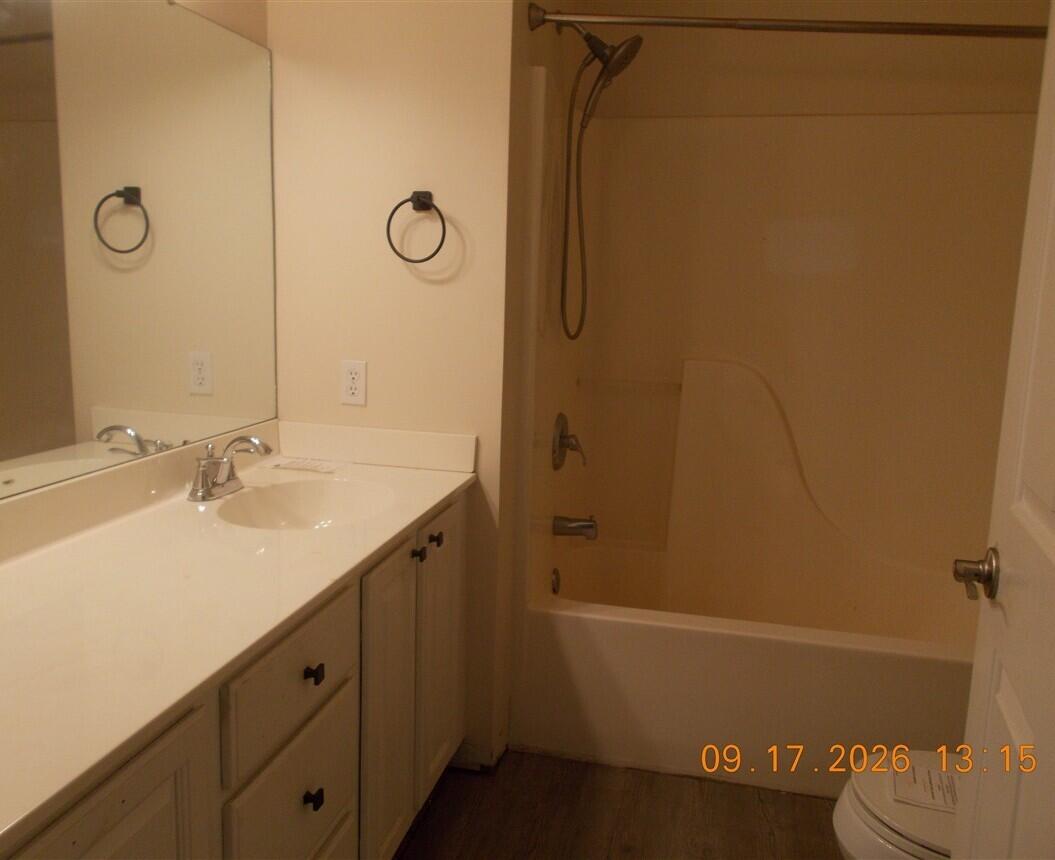 Bathroom with a long white vanity, large mirror, and bathtub with shower.