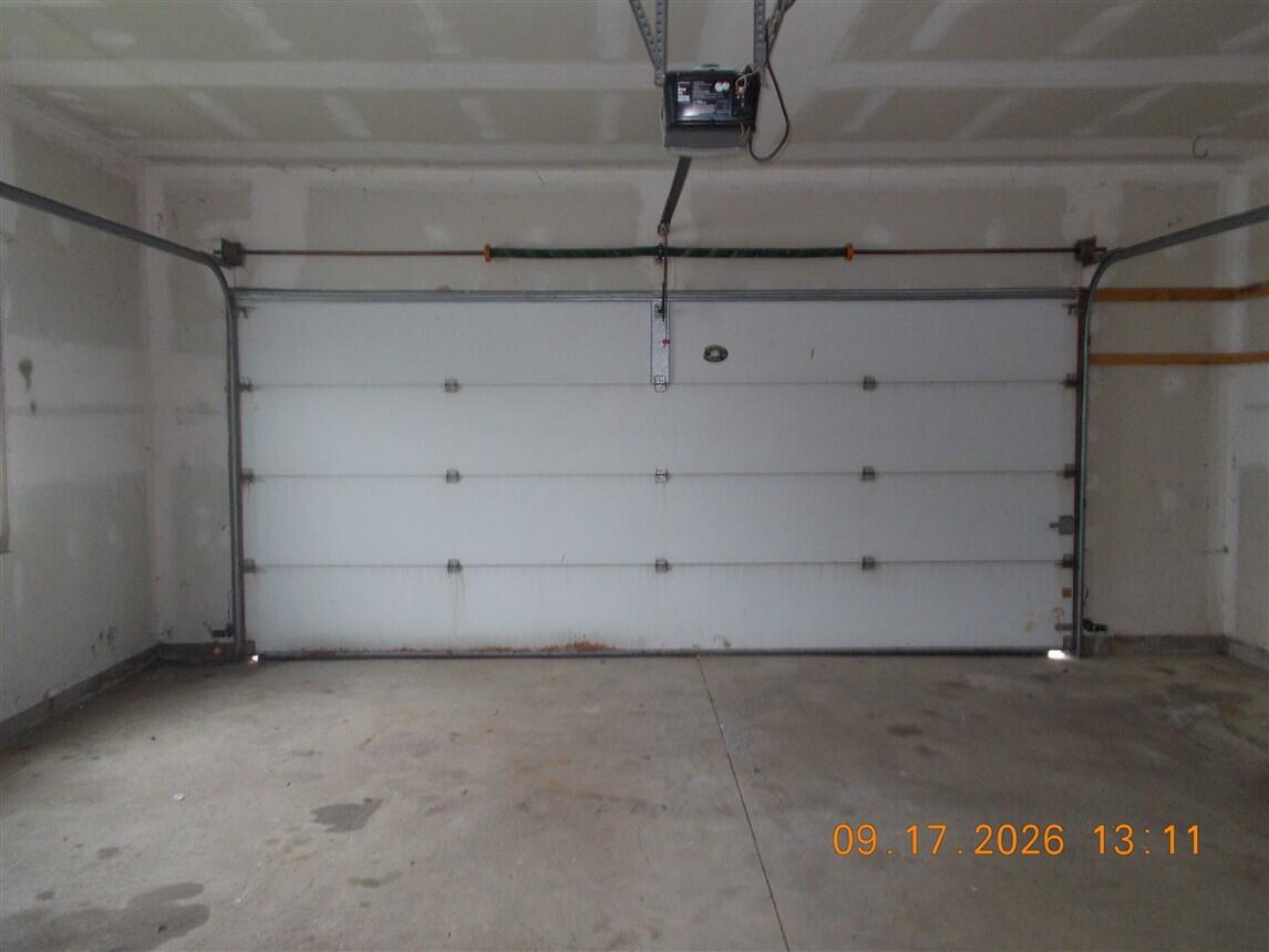 Empty garage with a closed white overhead door and bare concrete floor.