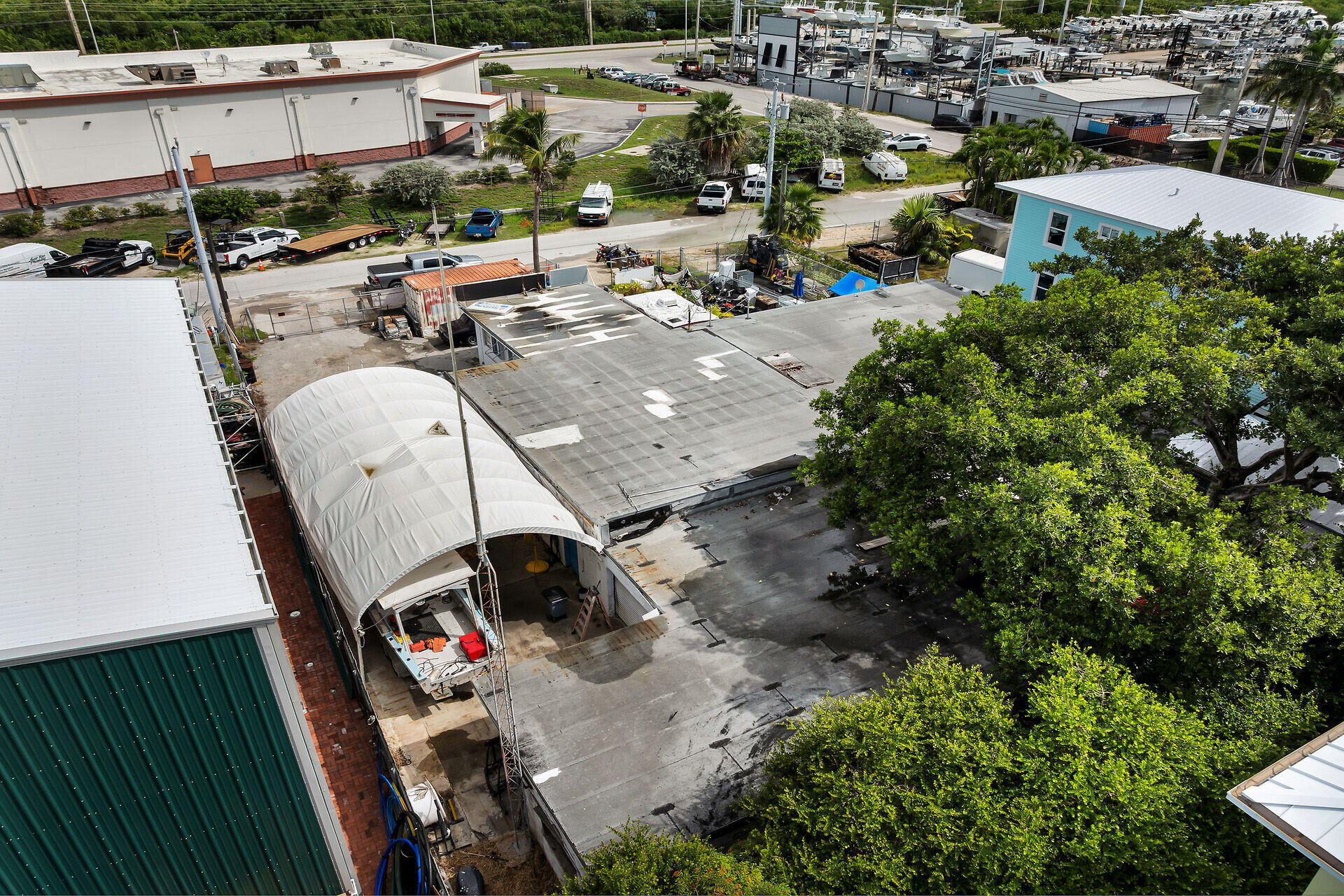 Aerial view of flat-roofed commercial buildings beside a boatyard filled with boats.
