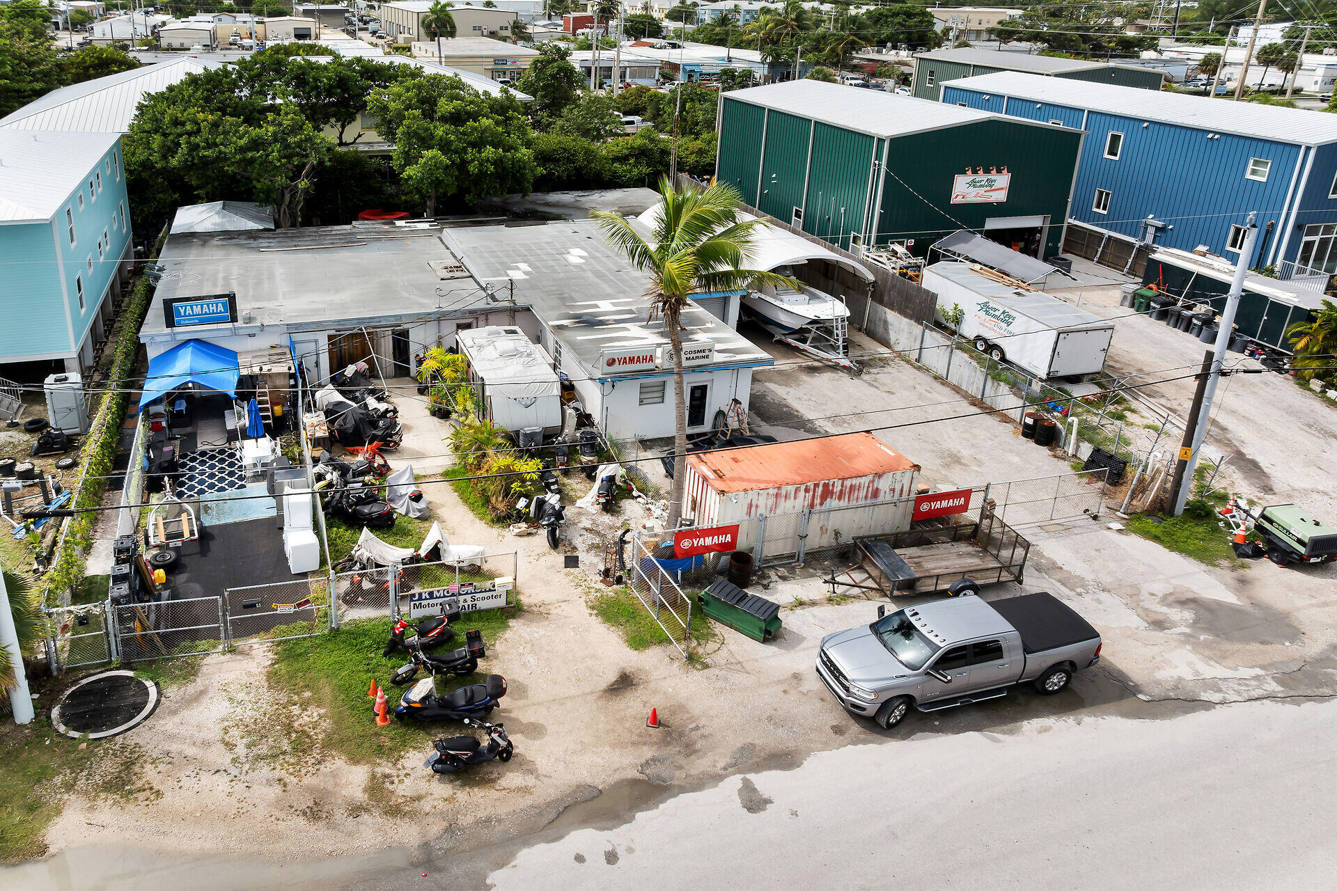 Aerial view of a marine repair yard with Yamaha signage, boats, scooters, and workshops.
