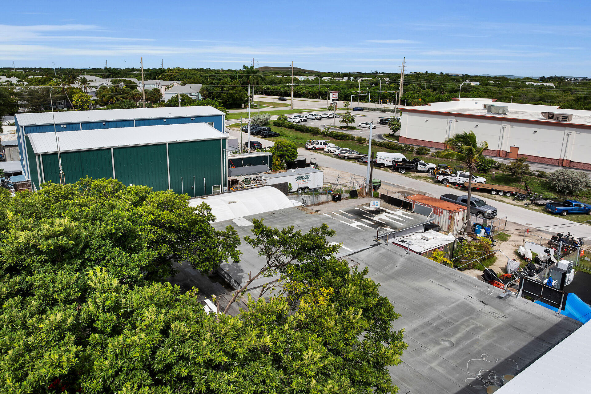 Aerial view of a commercial property with warehouse buildings, a paved yard, and parked work vehicles.