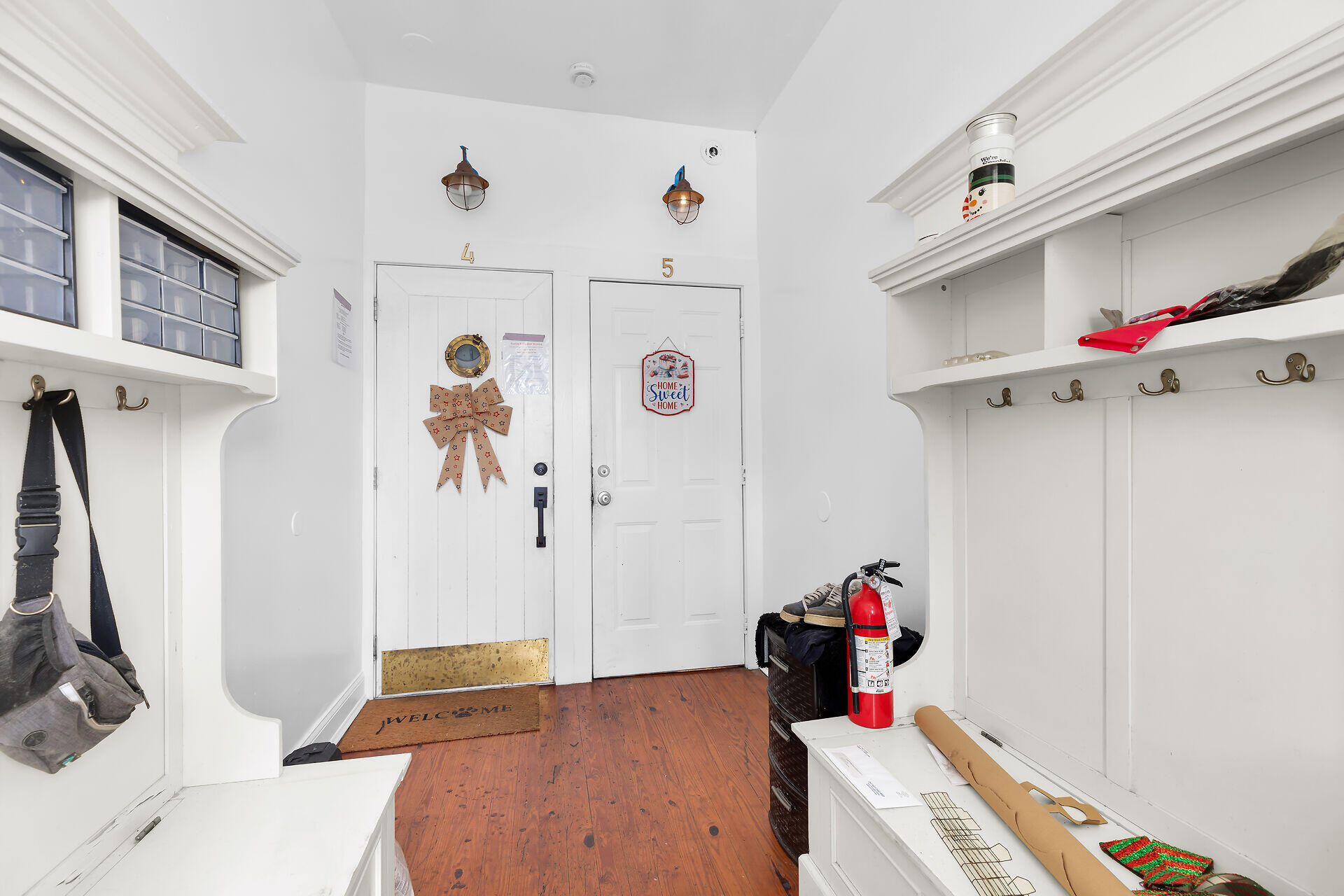 Entry vestibule with numbered doors, built-in white storage, and wood plank flooring.