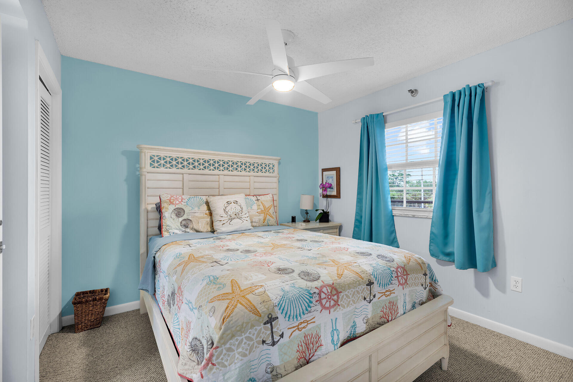 Bedroom with nautical-print bedding, a turquoise accent wall, and matching curtains.