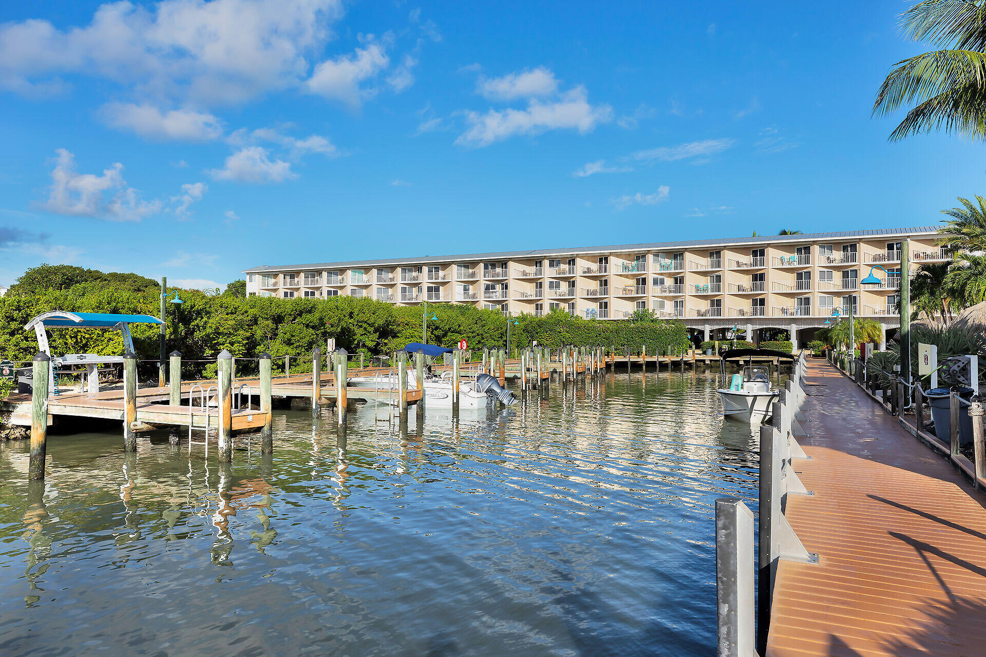 Waterfront condominium complex with marina docks, boats, and a boardwalk along the canal.