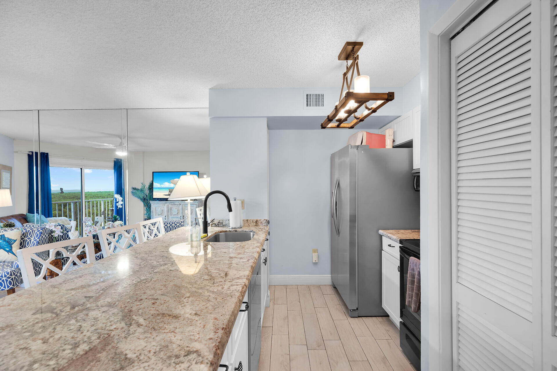 Condo kitchen with a long granite breakfast bar, stainless appliances, and an open view to the living area.