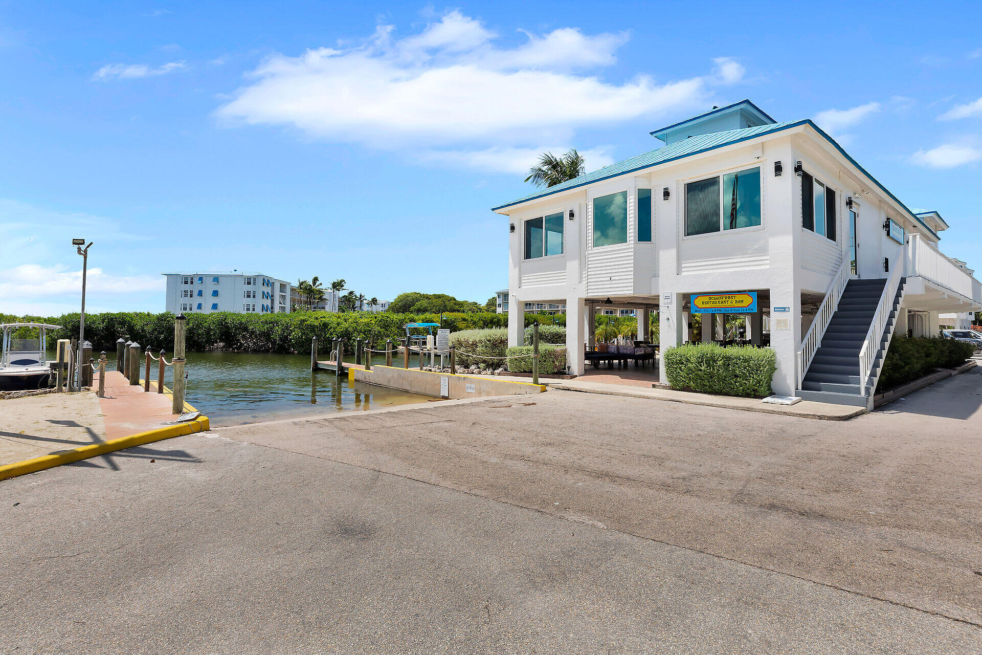 White waterfront building with blue roof, exterior staircase, and canal-side boat docks.