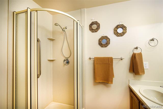 Bathroom with a curved glass shower enclosure, corner shelves, and a partially visible vanity.