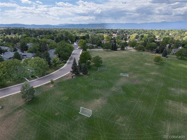 Aerial view of a neighborhood sports field with soccer goals, homes, and distant mountains.