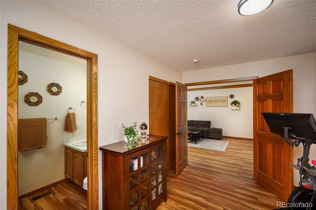 Entry hall with wood floors, bathroom doorway, wooden cabinet, and open doors to a sitting room.
