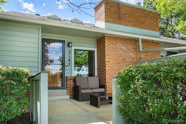 Front entry with pale green siding, brick facade, and a covered patio with outdoor seating.