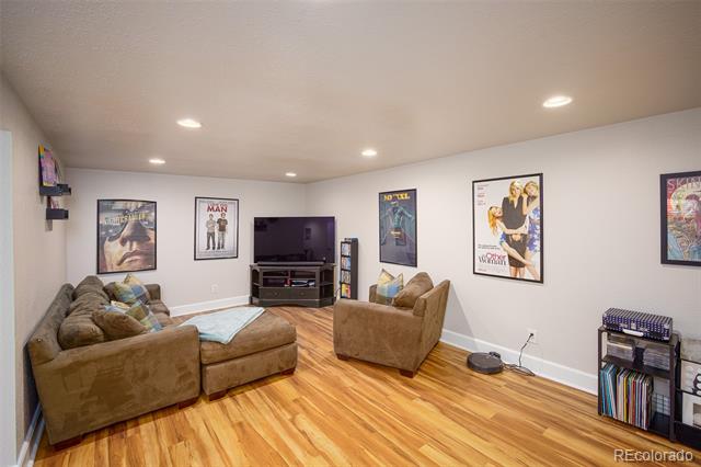 Living room with brown sofas, a television, framed posters, and warm wood flooring.