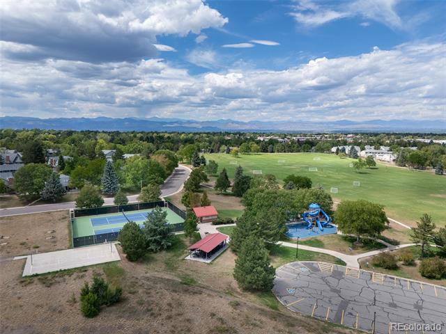 Aerial view of a neighborhood park with sports fields, tennis courts, playground, and distant mountains.