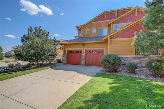 Two-story home with a two-car garage, colorful siding, stone veneer, and a wide driveway.