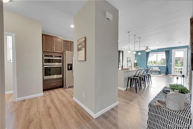 Open-plan kitchen and living area with a bar-seating island, wood cabinetry, and blue walls.